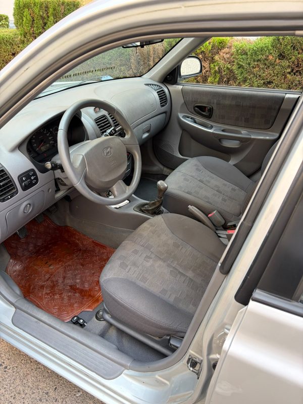 Interior Hyundai Accent gasolina LC 1.3 con asientos grises, volante y palanca de cambios en buen estado